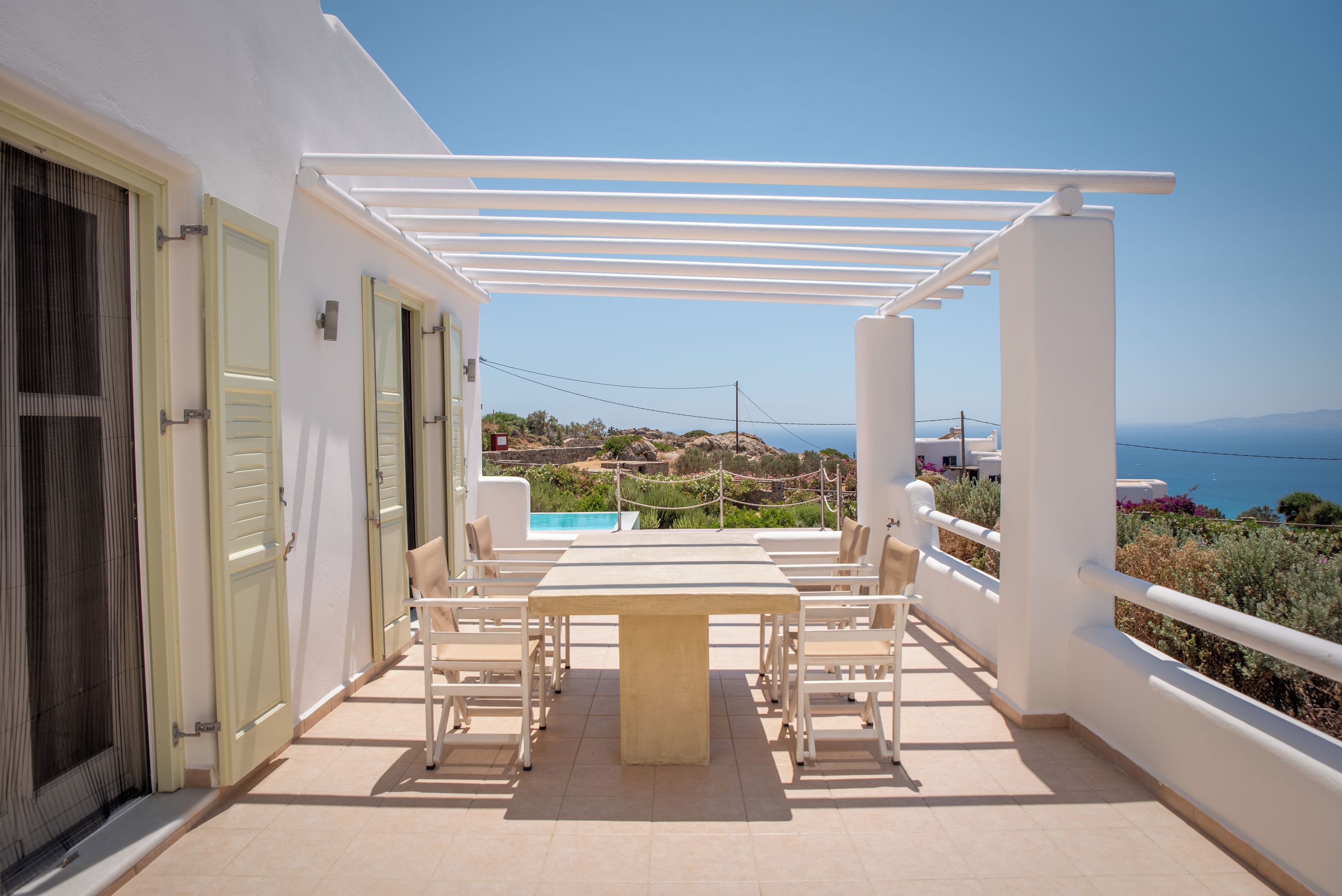 Une terrasse avec une table et des chaises, une piscine et une vue sur la mer.