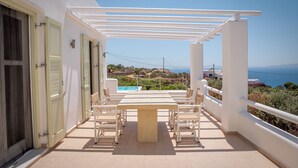 Une terrasse avec une table et des chaises, une piscine et une vue sur la mer.