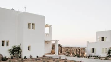 A white building with multiple windows and a stone wall in the background.