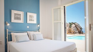 Une chambre à coucher avec un lit, deux lampes fixées au mur et une vue sur une piscine, visible à travers une porte ouverte.