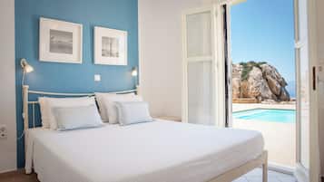 Une chambre à coucher avec un lit, deux lampes fixées au mur et une vue sur une piscine, visible à travers une porte ouverte.