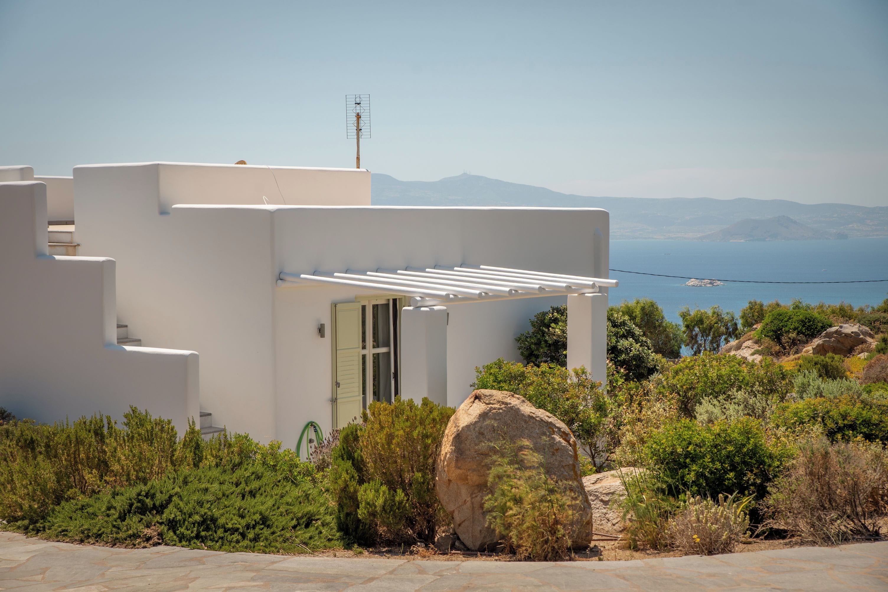 A modern building with a white facade, a door, and a small balcony.