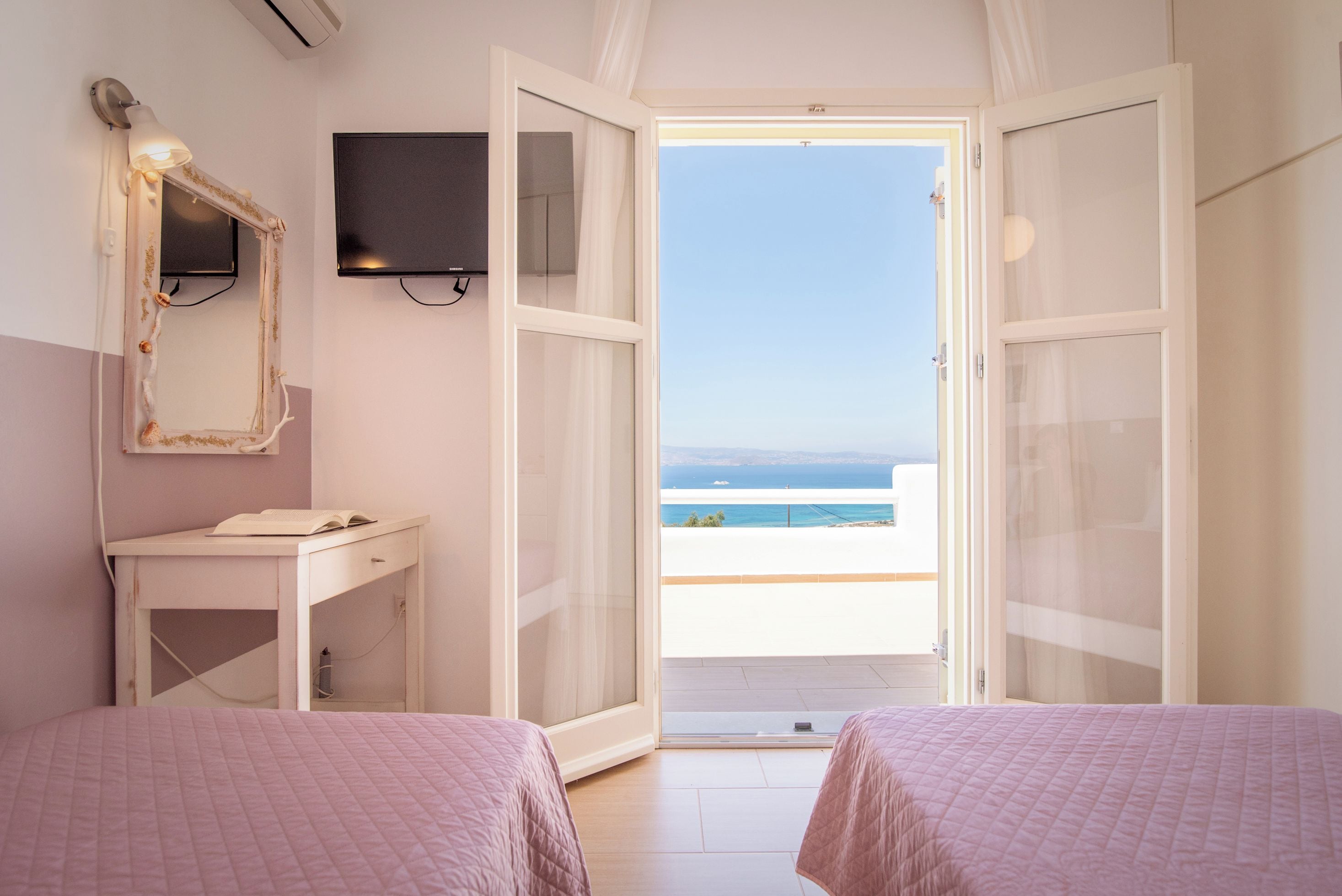 Une chambre avec deux lits, une télévision et vue sur la mer.