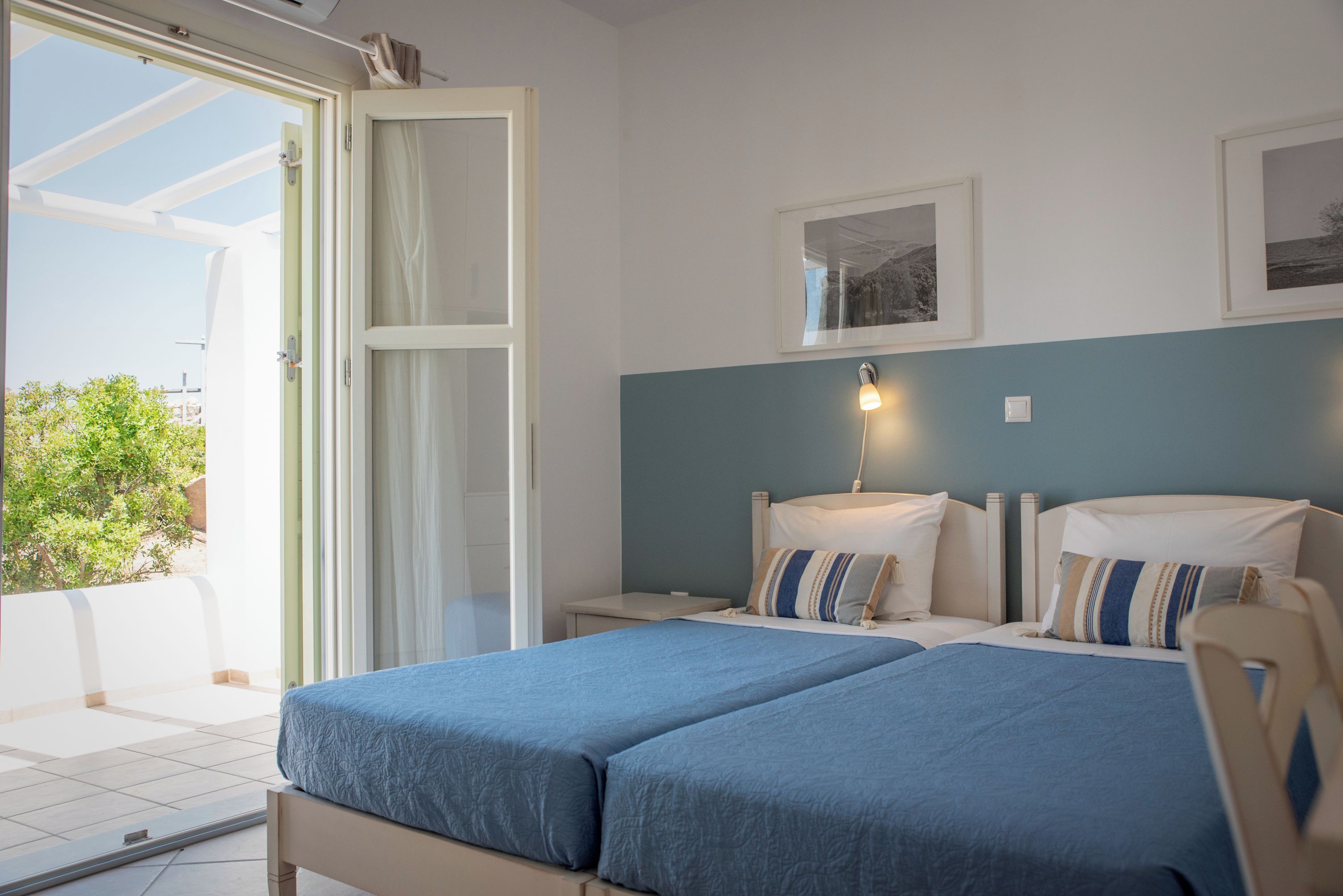 A bedroom with a bed, bedside tables, a nightstand, a window, and a wall-mounted picture.