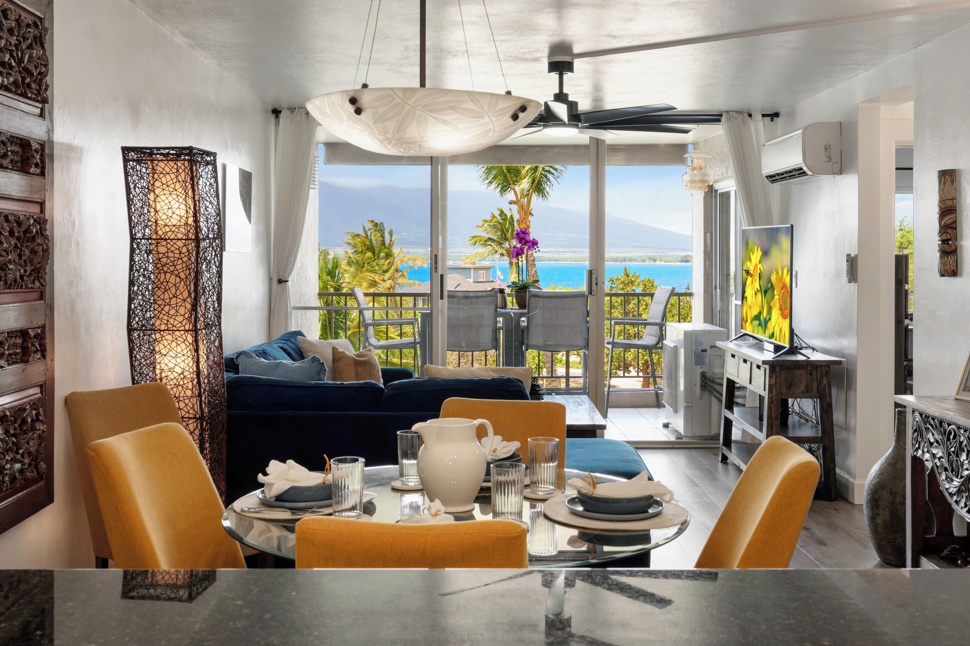 Un salon moderne avec vue sur la mer, un coin repas avec une table dressée pour deux personnes, et un balcon offrant une vue panoramique.