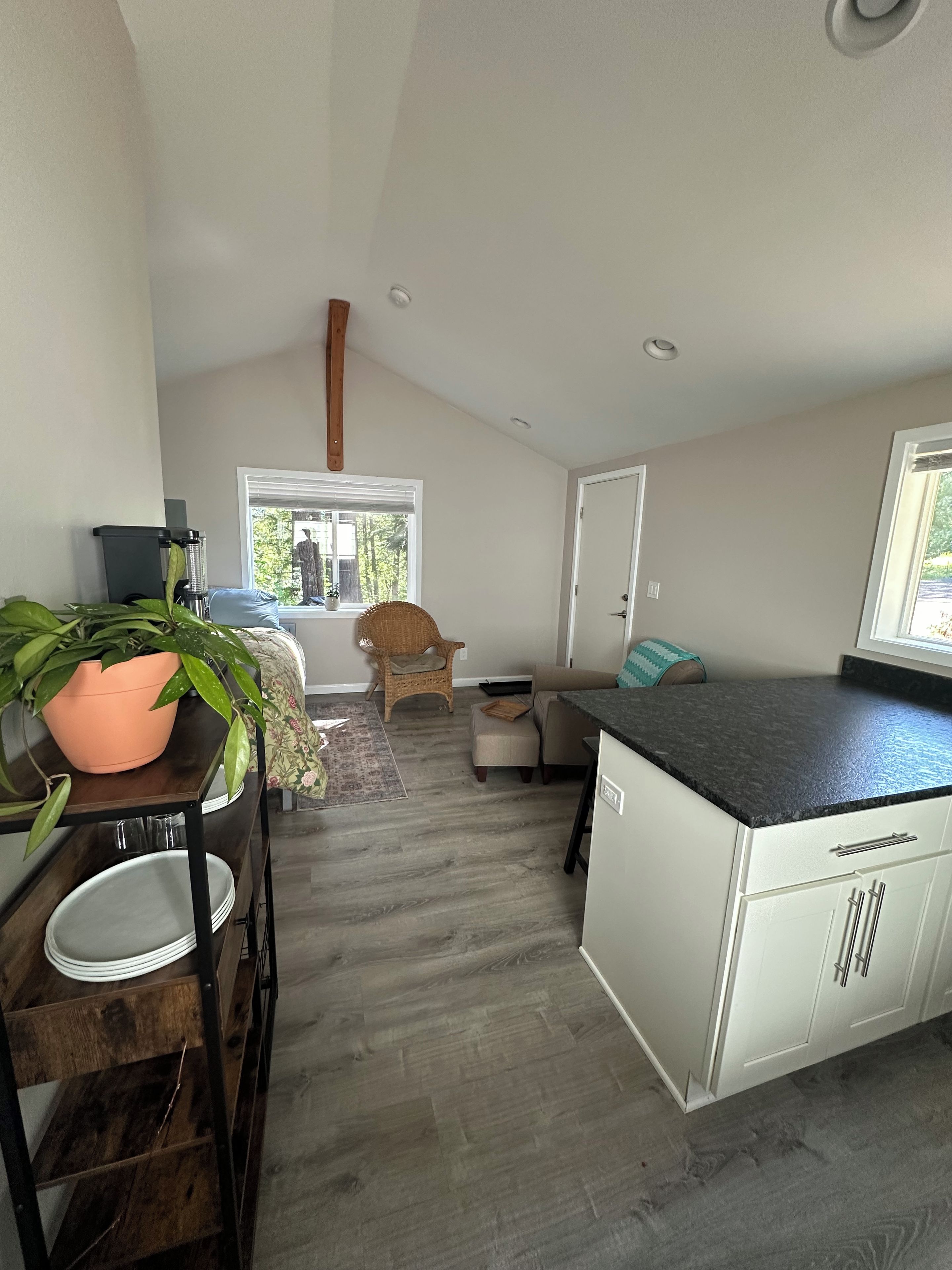 A compact kitchen with a dining area, a wooden floor, and a view through a window.