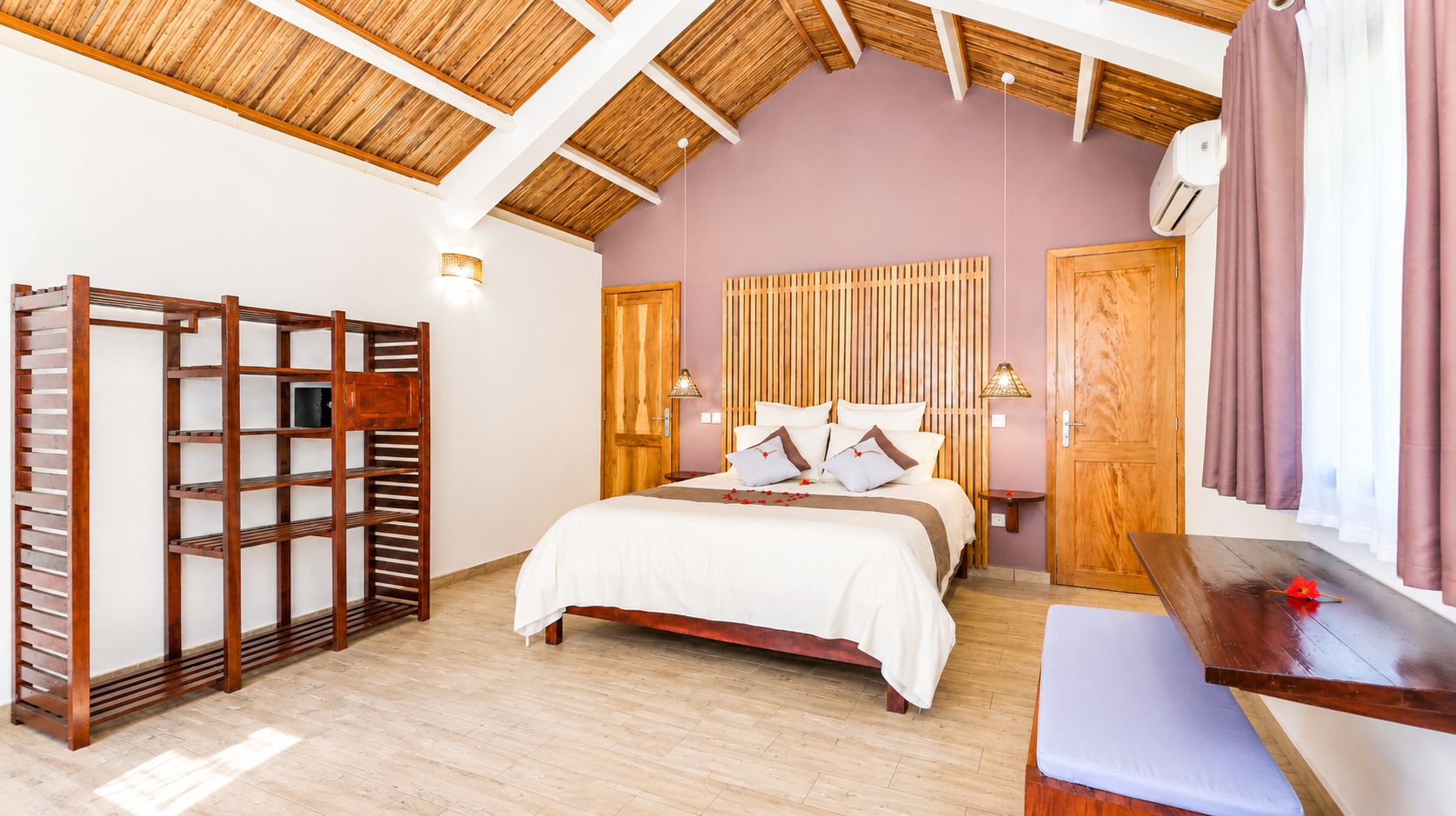 Ein Schlafzimmer mit einem Bett, einem Holz-Kopfteil, einem Regal, einem Nachttisch und einem Fenster mit Vorhängen.