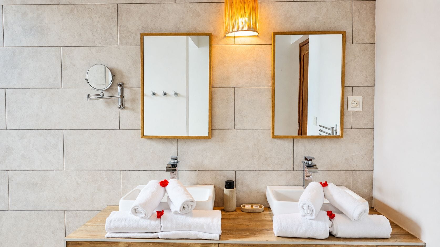 A bathroom with two sinks, each with a mirror above. There are towels on the sinks and a bottle of soap.