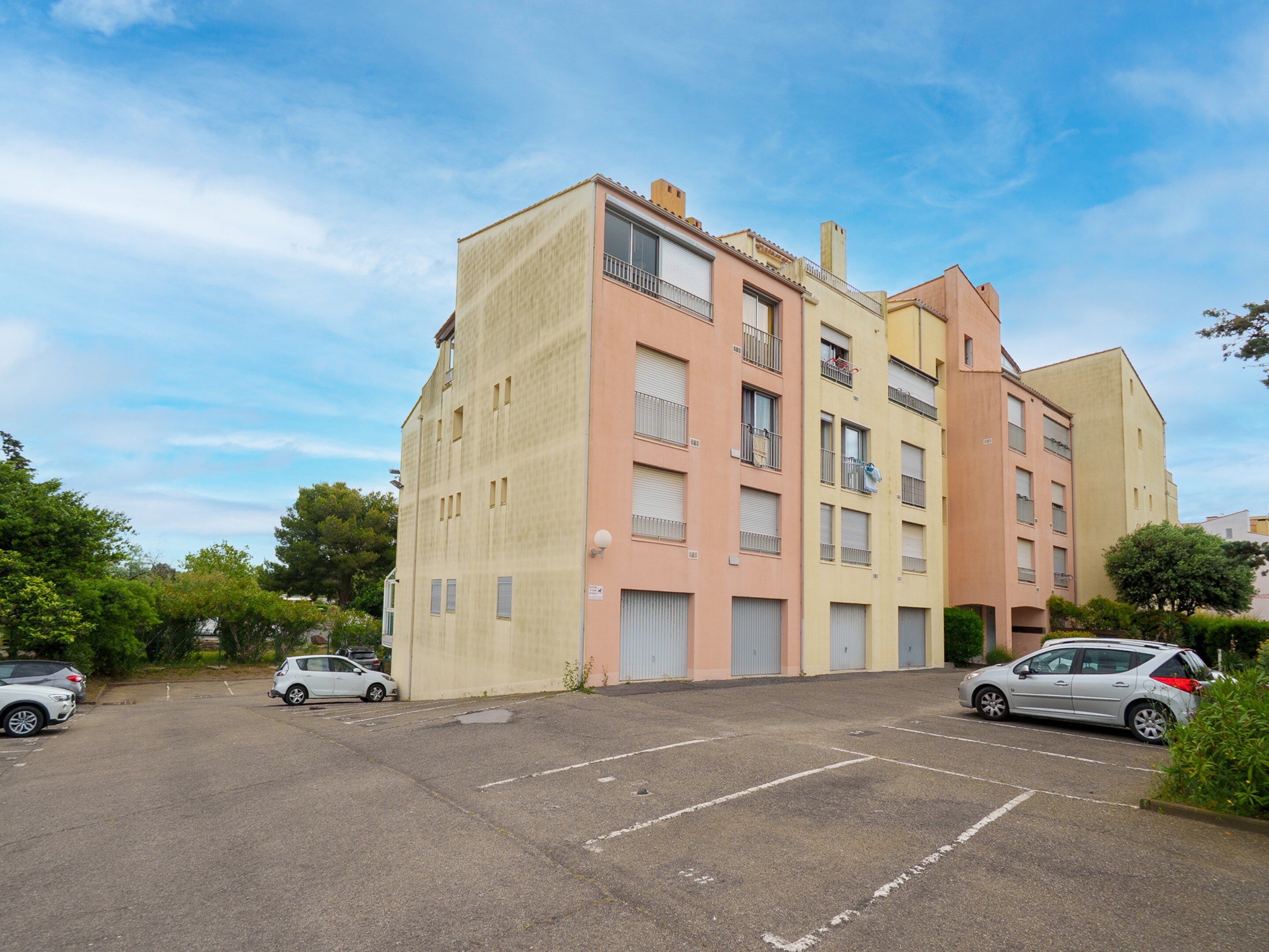 Un immeuble résidentiel à plusieurs étages avec un parking situé à l’avant.