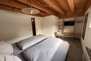 Ein Schlafzimmer mit Bett, Sessel, Fernseher und einer Tür.