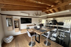 Eine moderne Küche mit einer großen Kochinsel, eingebauten Geräten und einem Essbereich mit Holztisch und Stühlen.