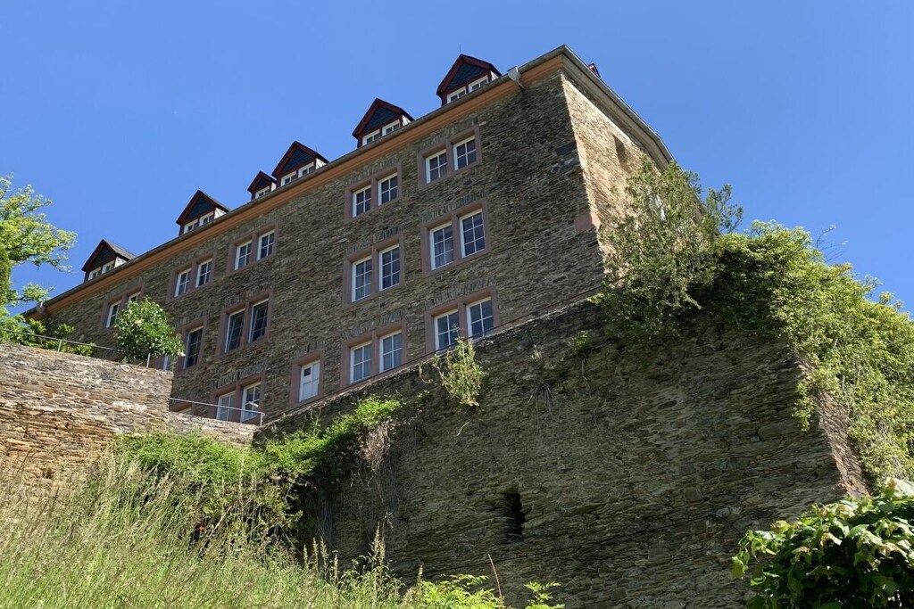 Ein mehrstöckiges Gebäude aus Stein mit flachem Dach und mehreren Fenstern.