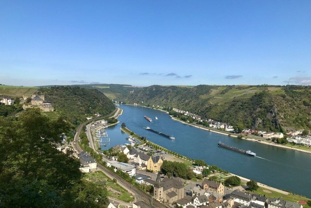 A river with boats, a town with buildings, and hills in the background.