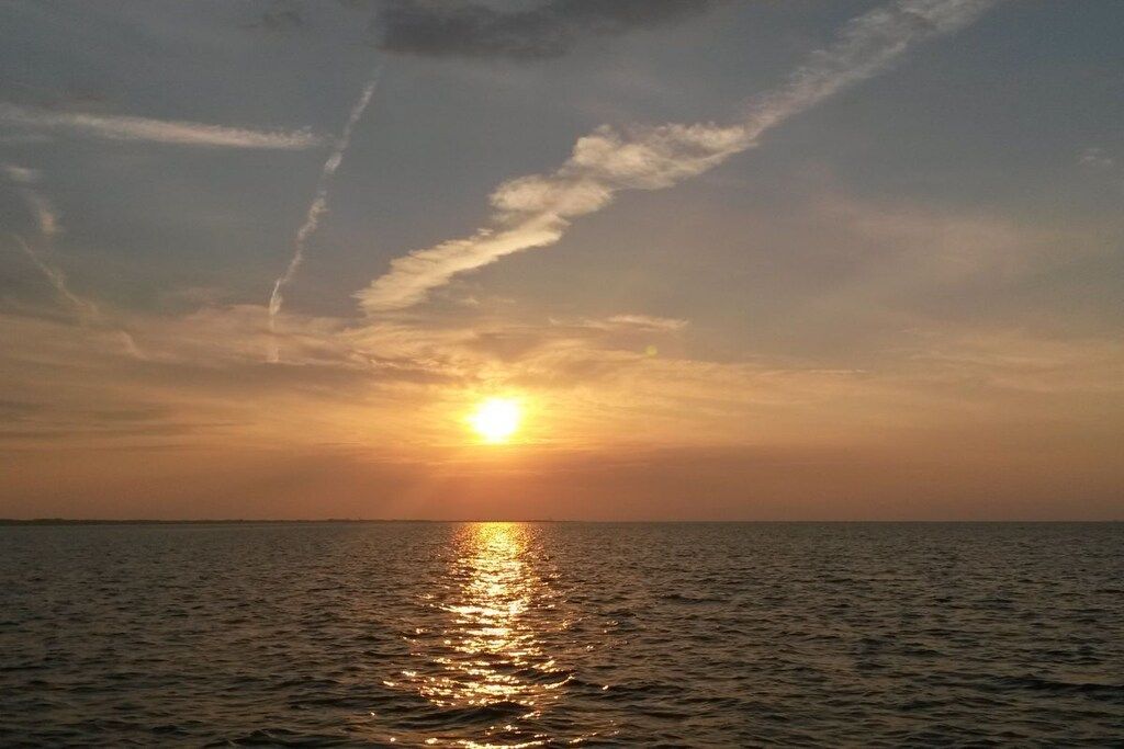 A sunset over a body of water with a clear horizon.
