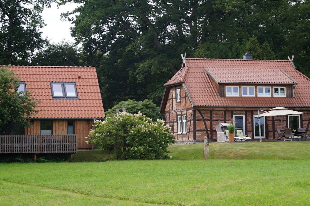 Ein zweistöckiges Haus mit rotem Ziegeldach, einem Balkon und einem Garten.