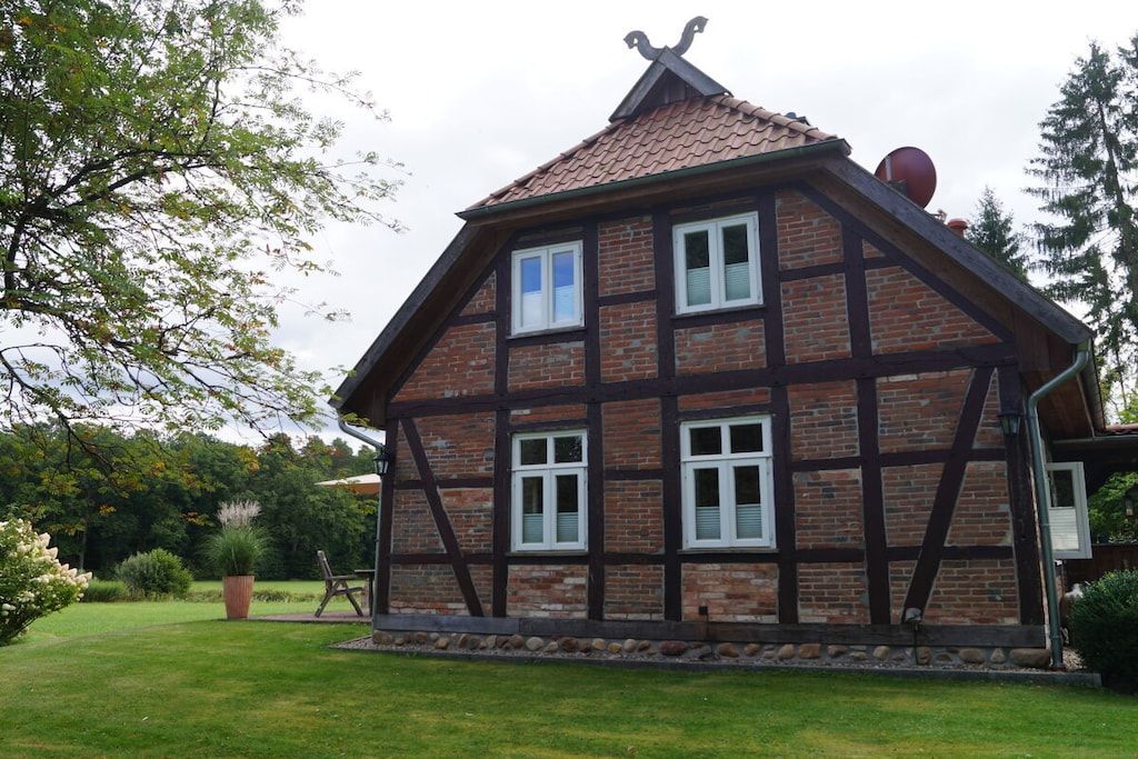 Uma casa tradicional de enxaimel com telhado inclinado, várias janelas e chaminé.