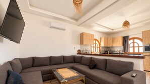 A modern living room with a sectional sofa, a coffee table, and a flat-screen TV. - 4-bedroom villa with private bathrooms, a pool, and air conditioning, near the airport (Essaouira)