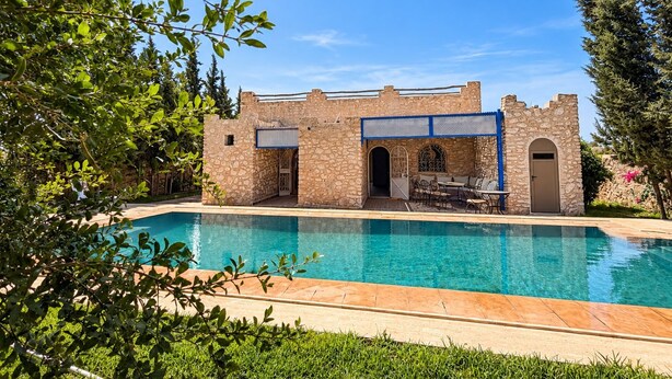 A stone building with a pool, surrounded by greenery. - 4-bedroom villa with private bathrooms, a pool, and air conditioning, near the airport (Essaouira)