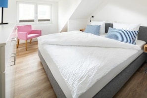 A bedroom with a large bed, a desk, a chair, and a window. - Holiday apartment in Juist with swimming pool (Juist)
