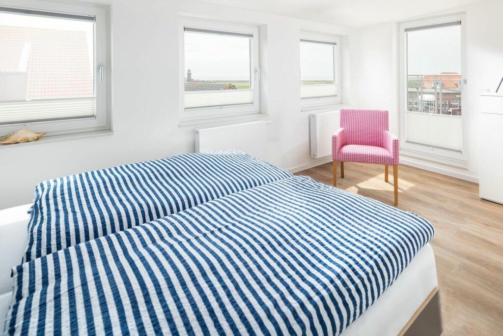 Ett sovrum med en säng, ett element, ett fönster och en stol.