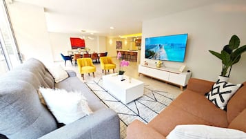 Uma sala de estar moderna com sofá, mesa de centro e televisão de tela plana.