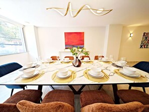 A modern dining room with a marble table set for a meal, surrounded by upholstered chairs. - Leonora 3 · 180 m² steps from Masaryk and Antara · 4 baths (Ciudad de México)