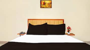 Una habitación de hotel con una cama, una mesita de noche, un teléfono y un cuadro en la pared.