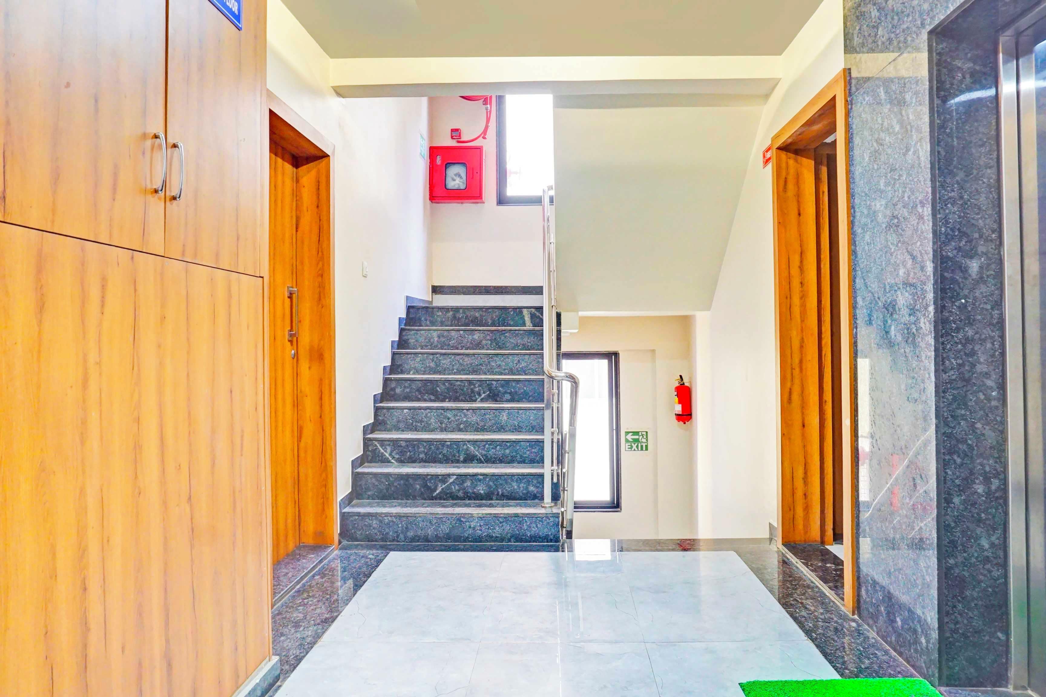 A hotel corridor with a marble floor, wooden doors, and a staircase leading to an upper level.