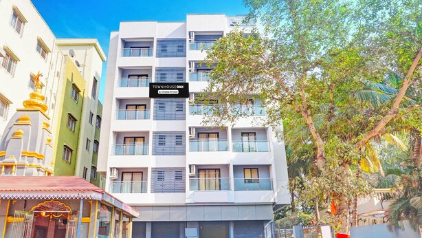 Un edificio de varios pisos con un cartel que indica 'TOWNHOUSE OAK' y 'Company Serviced'.