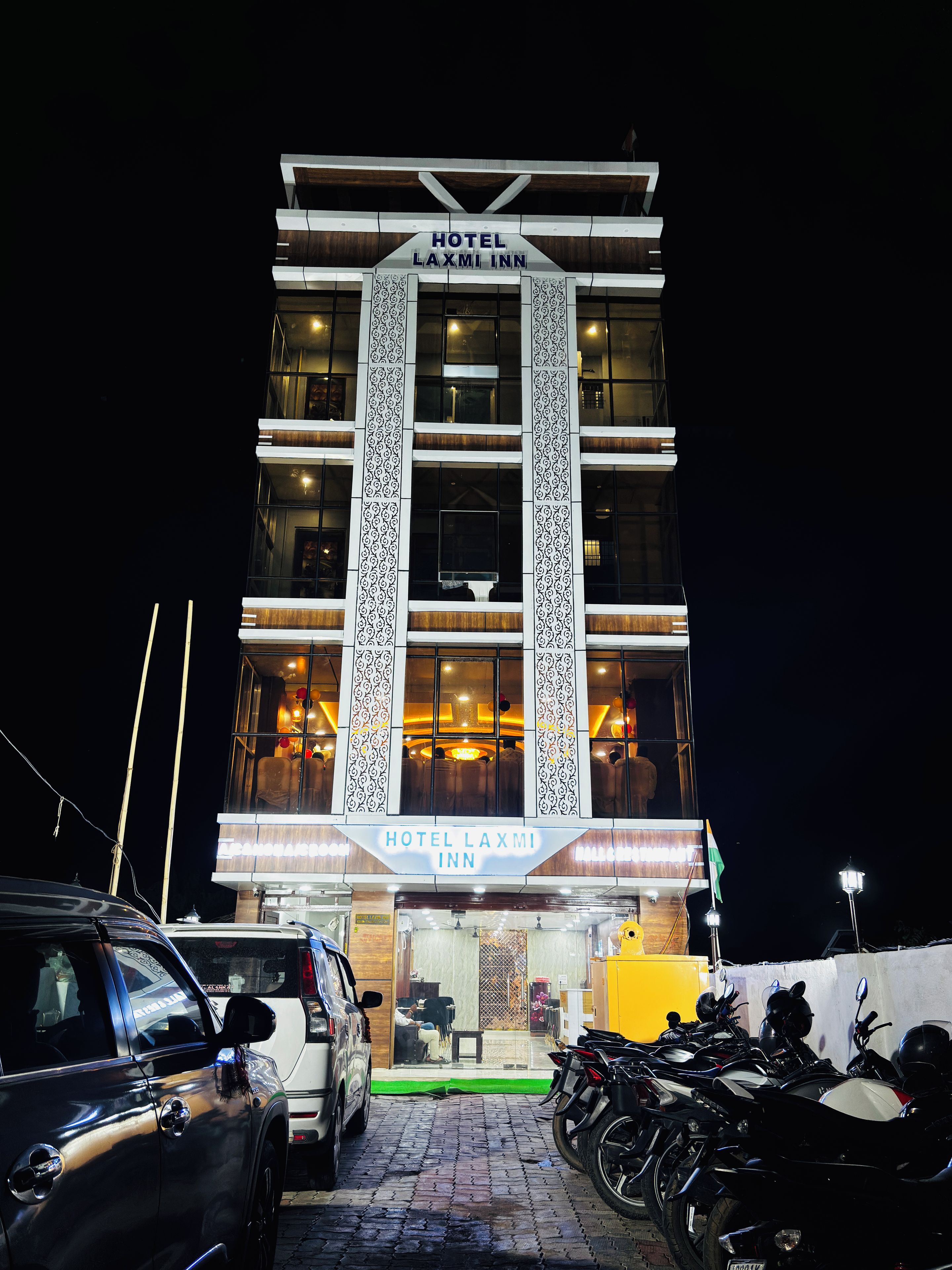 Un hôtel à plusieurs étages, reconnaissable à son grand panneau indiquant « HÔTEL LAXMI INN ».