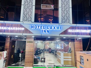 A hotel entrance with a reception desk, seating area, and a sign indicating 'HOTEL LAXMI INN' and 'CANCUN/CROOM' services. - Hotel Laxmi Inn (Danapur)