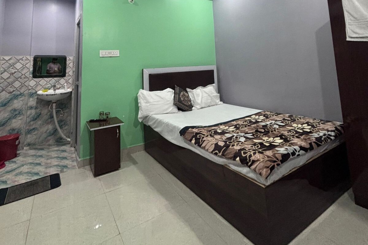 A bedroom with a bed, a ceiling fan, a nightstand, a mirror, and a bathroom with a sink.