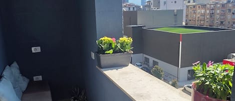 Un balcón con zona de estar, plantas en macetas y vistas a la ciudad.
