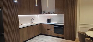 Una cocina moderna con armarios de madera, lavavajillas negro y una encimera con cafetera.