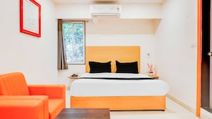 Una habitación de hotel con una cama, una mesita de noche, un teléfono, un cuadro en la pared y un equipo de aire acondicionado.