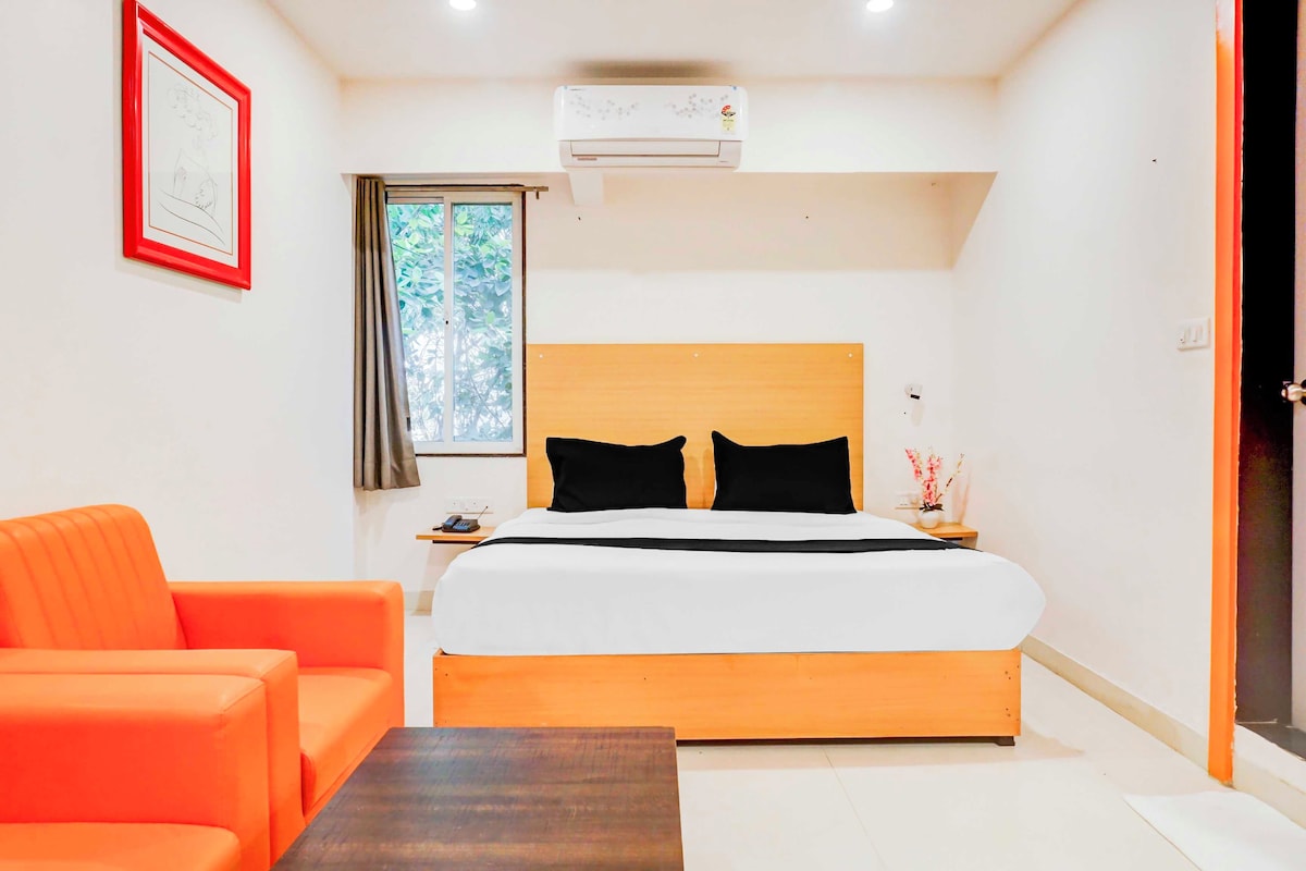 Une chambre d’hôtel comprenant un lit, une table de chevet, un téléphone, un tableau encadré au mur et un appareil de climatisation.