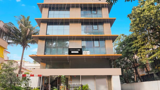 Un edificio de varios pisos con un letrero que indica 'Company Serviced' y una unidad de aire acondicionado visible.