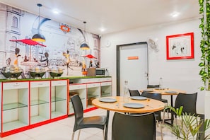 L’intérieur d’un restaurant, avec une fresque murale, des tables, des chaises et un four à micro-ondes.
