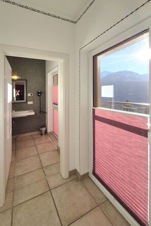 Een hotelkamer met een badkamer, een spiegel, een telefoon en uitzicht op bergen.