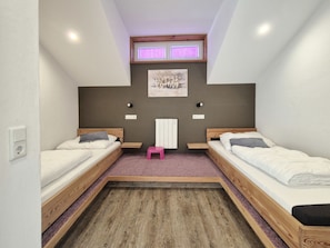 A small, modern bedroom with two beds, a small stool, and a radiator. - 7_HGG_Michaela by Interhome (Neukirchen am Großvenediger)