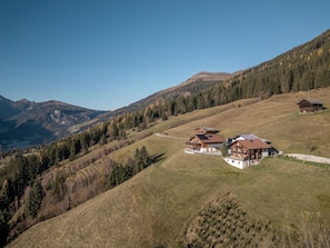 Un paysage montagneux avec un groupe de maisons en bois regroupées sur le versant d’une colline.
