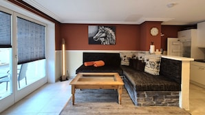 Una sala de estar con un sofá, una mesa de centro, una chimenea y una zona de cocina.