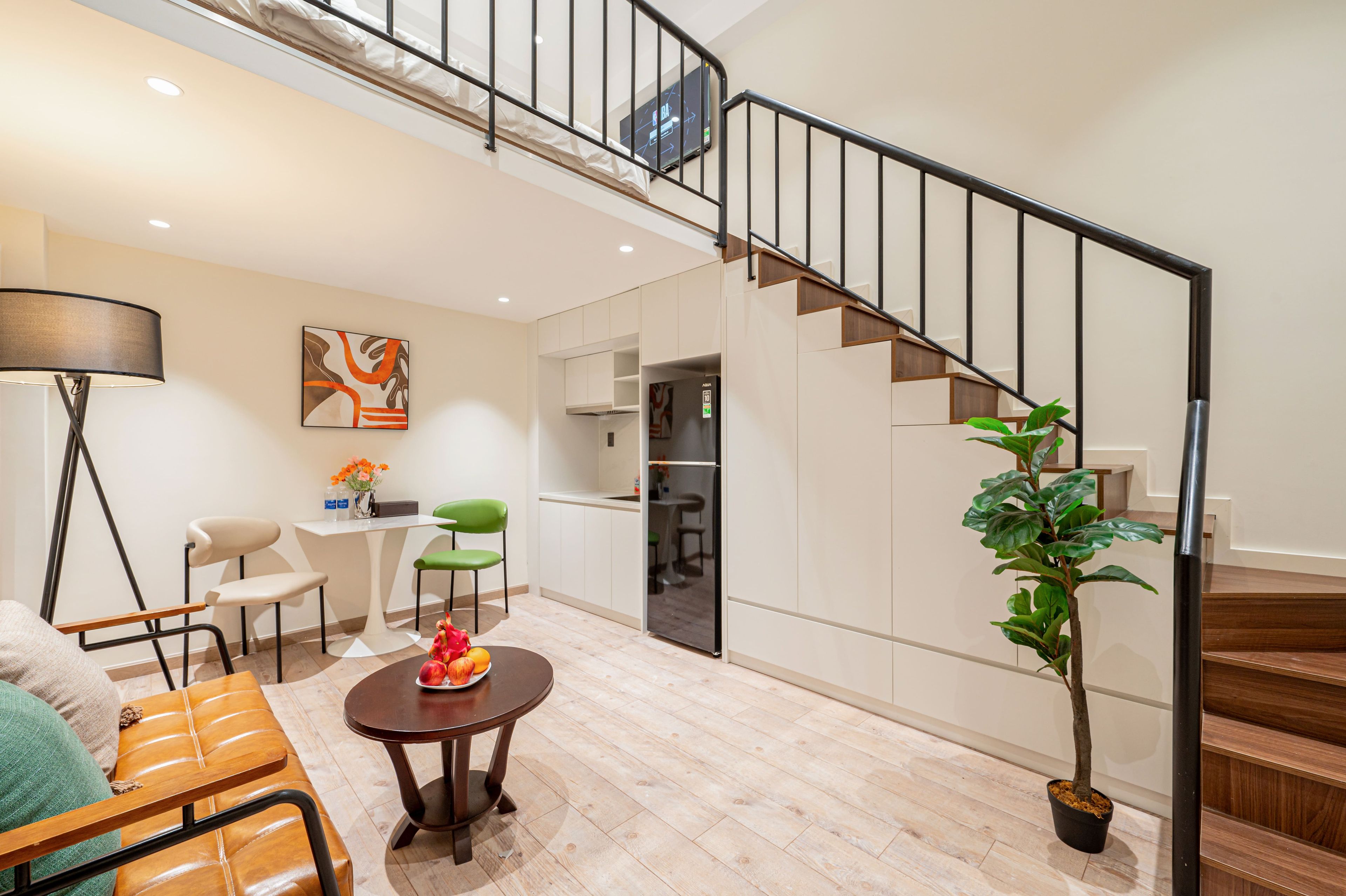 A modern living room with a dining area, a staircase, and a kitchen.
