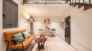 A modern living room with a leather sofa, a round coffee table, and a dining area with a white table and chairs.