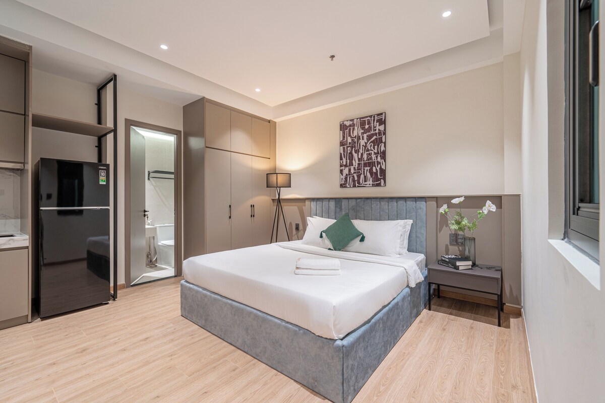 Een moderne slaapkamer met een bed, nachtkastje en uitzicht op de badkamer.