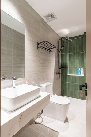 Een moderne badkamer met een grote spiegel, een wit wastafelmeubel, een toilet en een douchehoek.