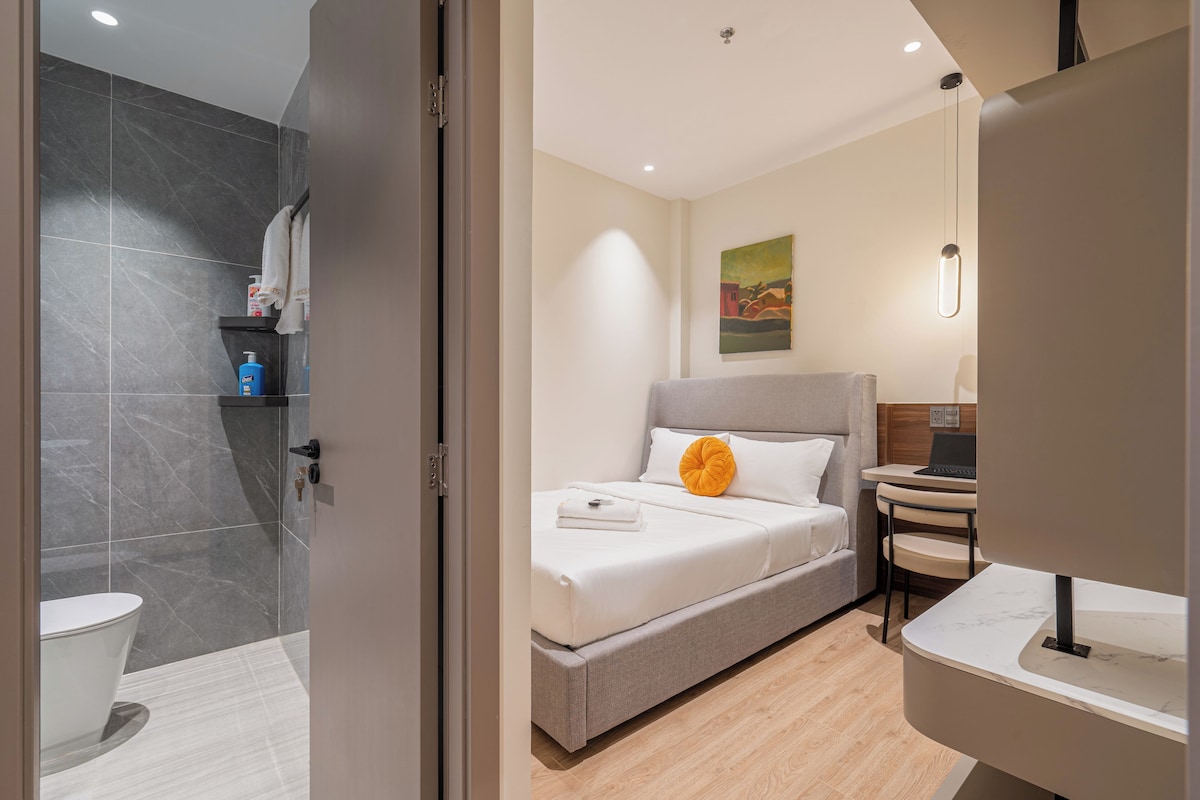 Een moderne hotelkamer met een bed, een bureau en een badkamer.