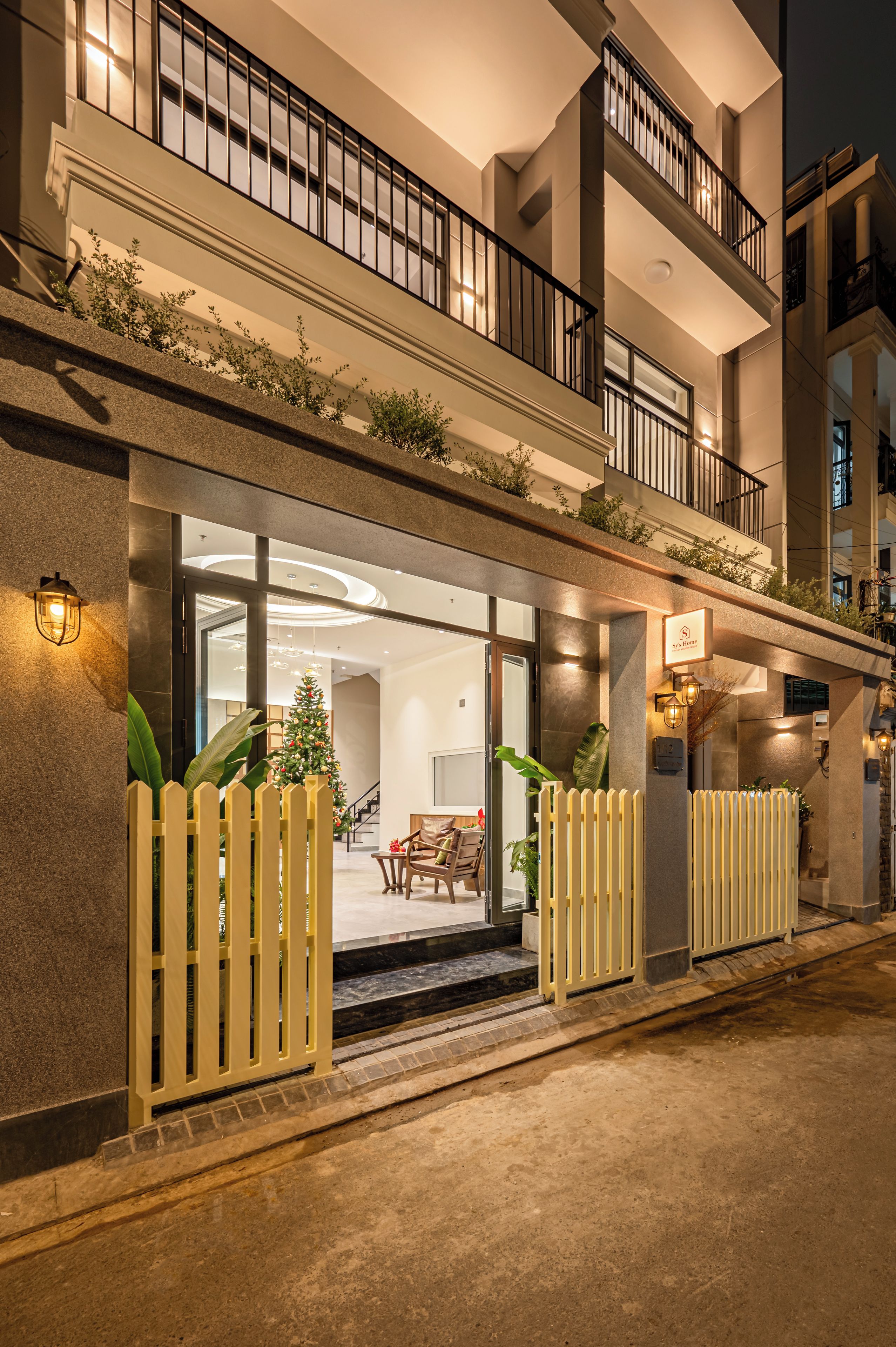 A hotel entrance with a glass door, a Christmas tree, and a balcony with railings.