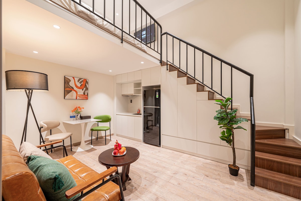 Een moderne woonkamer met een bank, een eettafel en een trap naar een hoger gelegen verdieping.