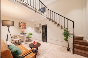 Una sala de estar moderna con un sofá, una mesa de comedor y una escalera que lleva a un nivel superior.